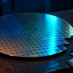 "Broadcom AI semiconductor revenue—silicon wafer on a workbench with individual chips cut from the edge."